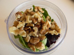 walnuts on top of mixed greens and nettle leaves in blender