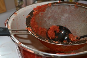 pushing tomatoes through a sieve