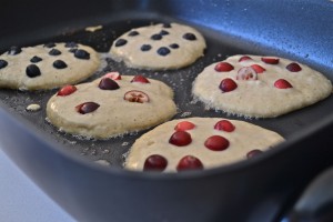 cranberry and blueberry pancakes on griddle